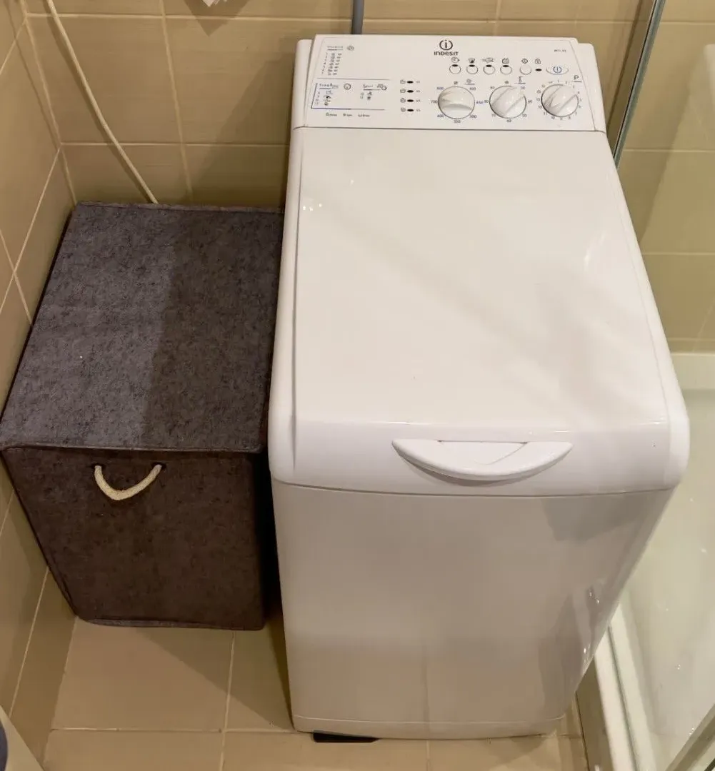 Bathroom with a washing machine and a laundry basket.