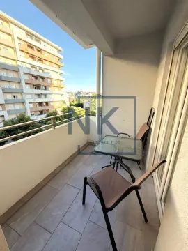 Small covered balcony with outdoor seating and a view of urban buildings. - image 9