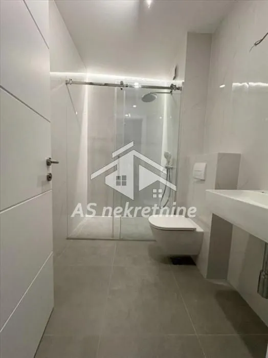 Moderno kupatilo sa tuš kabinom i sanitarijama.