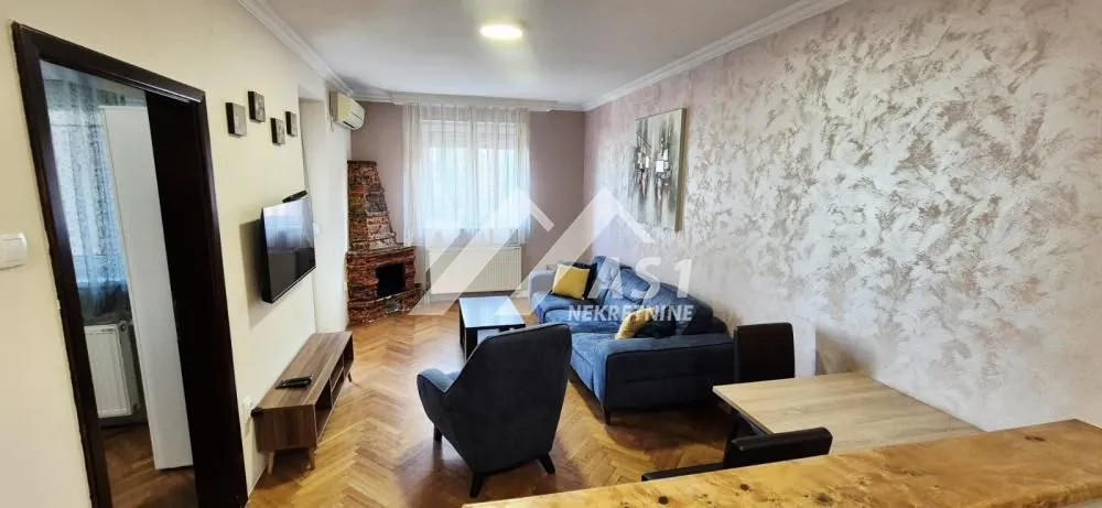 Dnevna soba sa garniturom, televizorom i trpezarijskim stolom.
