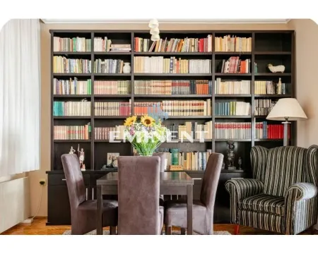 Living room with a large wooden bookcase, dining table, and an armchair. - image 18