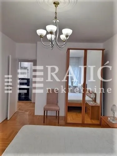 Furnished bedroom with a mirrored wardrobe and a chandelier.