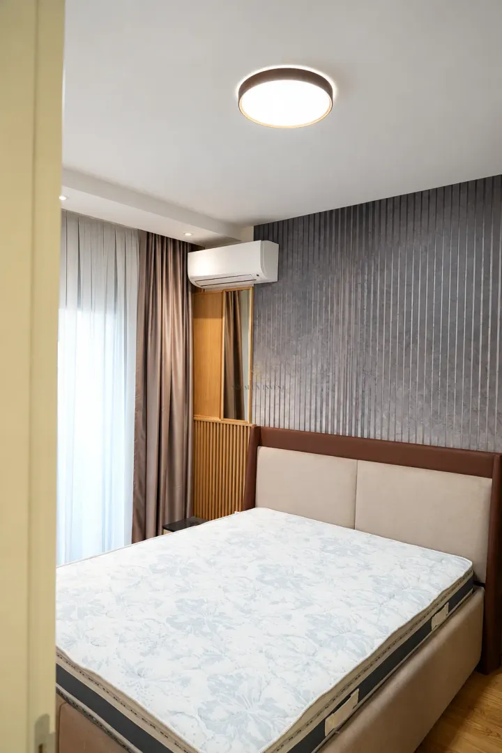 Modern bedroom with a double bed, air conditioning unit, and decorative wall panels.