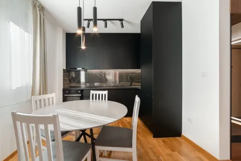 Moderna kuhinja sa crnim elementima i trpezarijskim stolom. - image 16