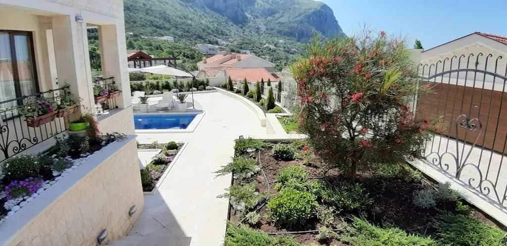 Dvorište sa bazenom i uređenim vrtom ispred kuće.