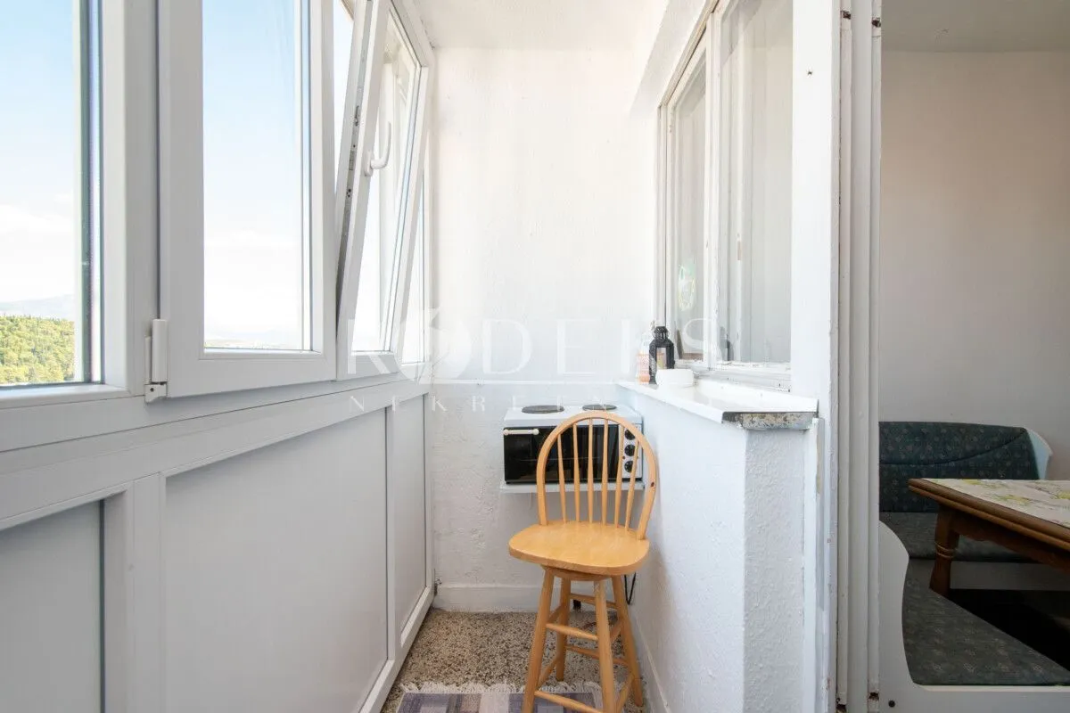 Enclosed balcony with a chair and a small stove.
