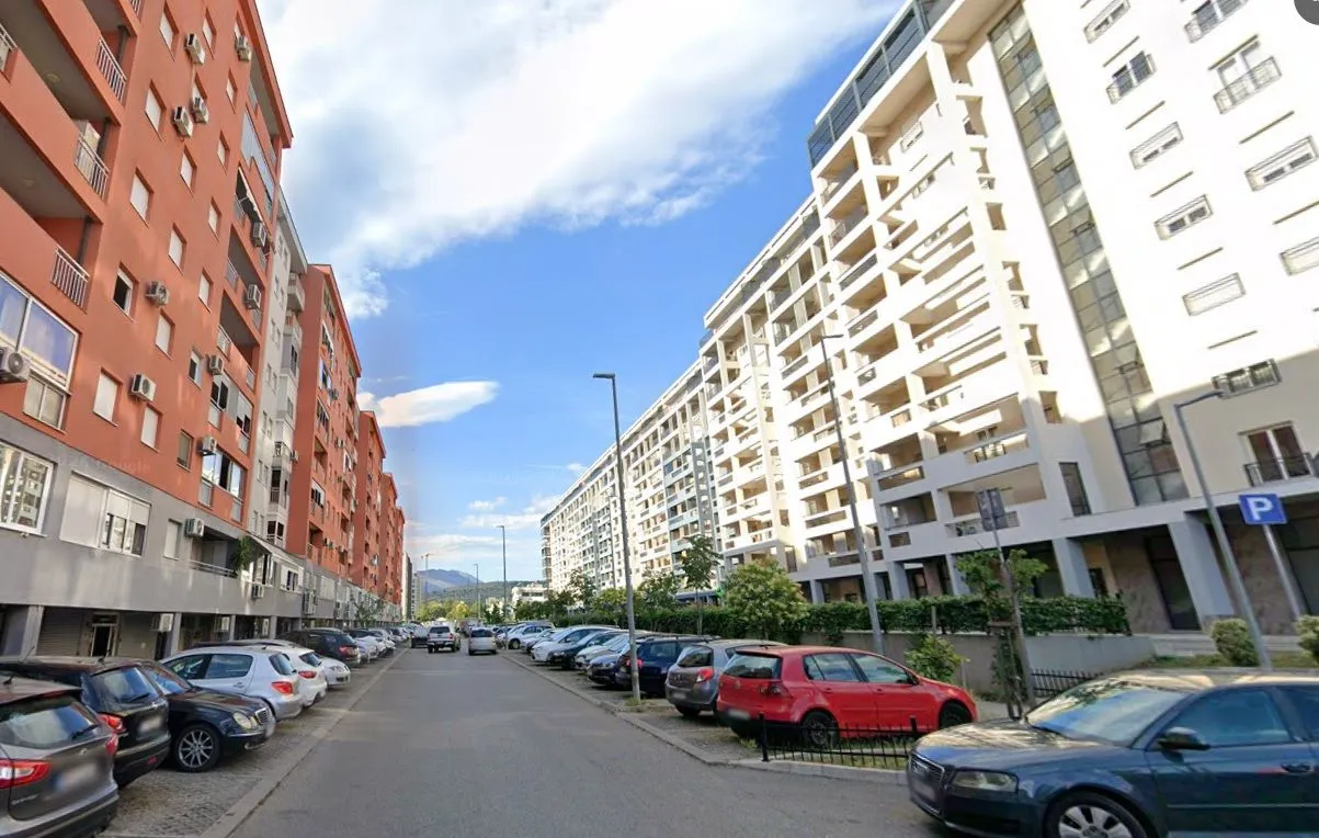 Pogled na ulicu i stambene zgrade sa parkingom.