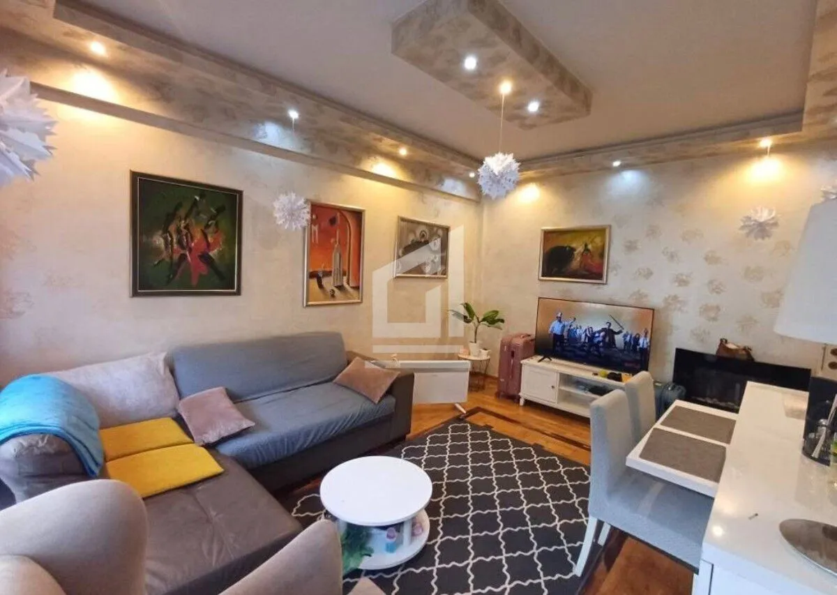 Living room with sofa, TV and dining table.