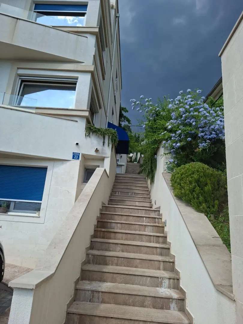 Spoljni dio zgrade sa stepeništem i uređenim zelenilom.