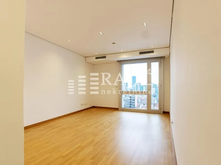 Empty room with parquet flooring and a large window.