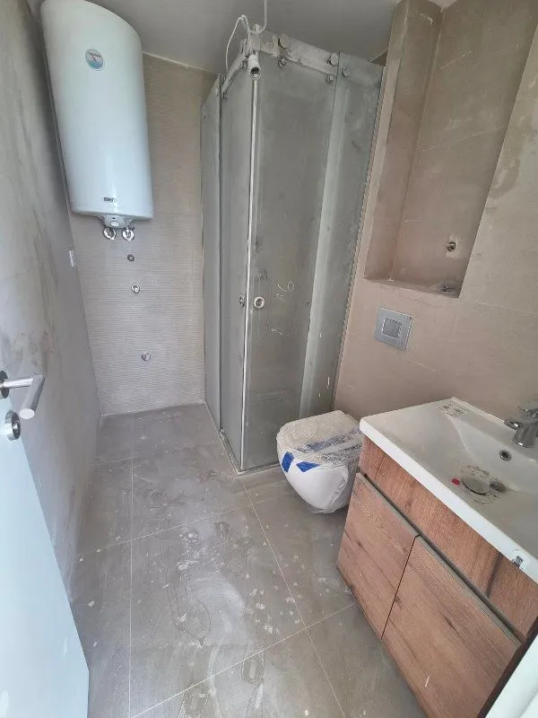 Kupatilo u fazi završnih radova sa tuš kabinom, umivaonikom i bojlerom.