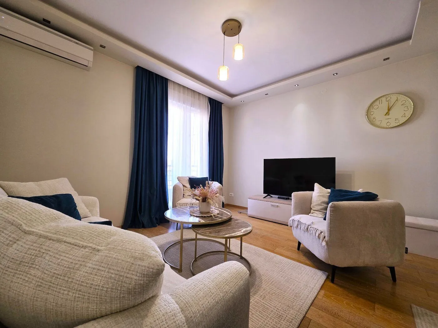 Uređena dnevna soba sa garniturom, stočićem i televizorom.