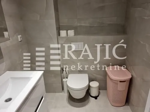 Modern bathroom with a washbasin, toilet, and grey tiles.
