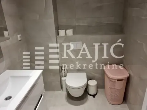 Modern bathroom with a washbasin, toilet, and grey tiles. - image 8