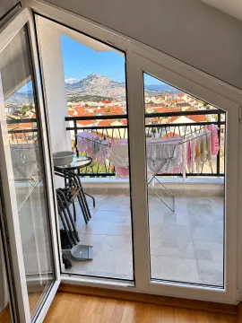 Pogled sa balkona na grad i planine sa sušilicom za veš. - image 5
