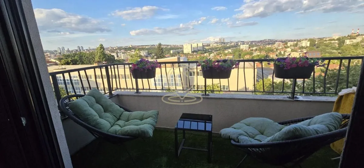 Namešten balkon sa garniturom za sedenje i pogledom na grad.