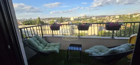 Namešten balkon sa garniturom za sedenje i pogledom na grad. - image 11
