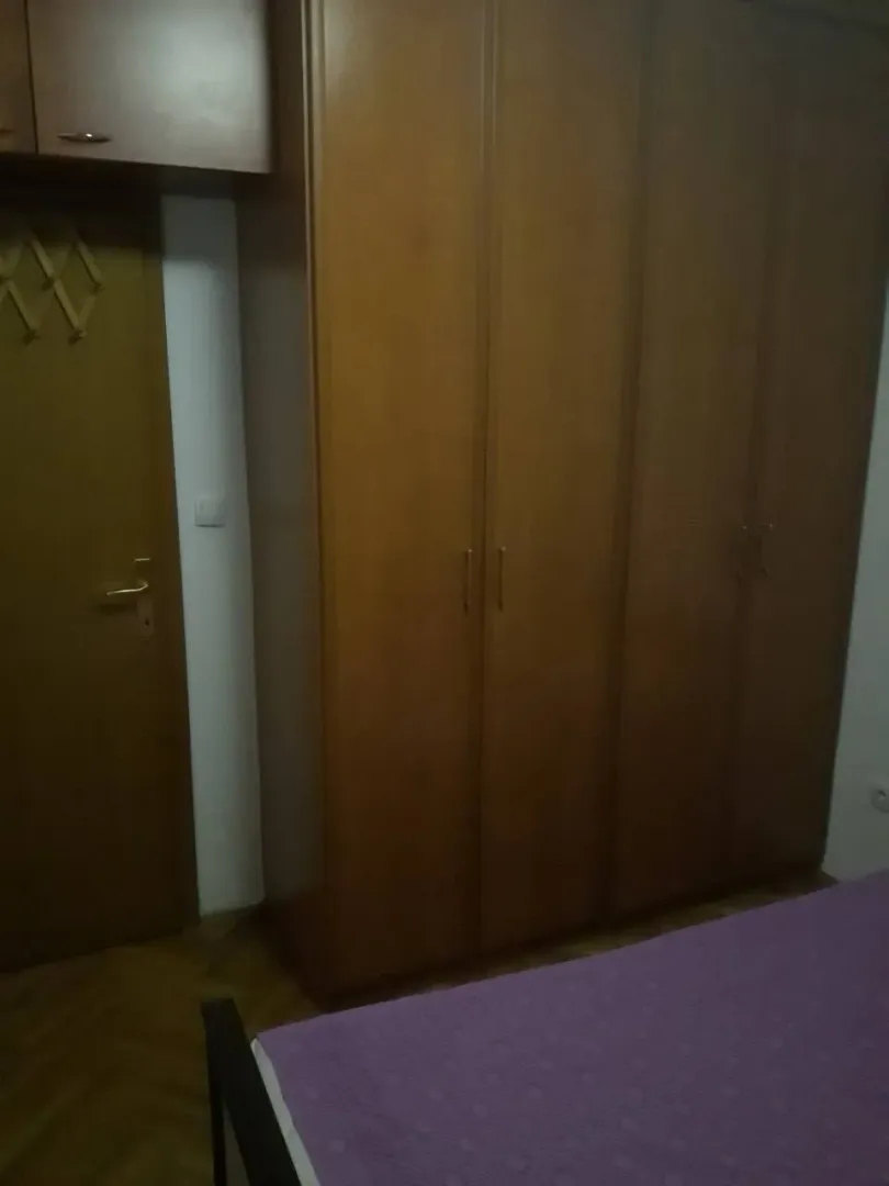 Spavaća soba sa drvenim plakarom i krevetom.