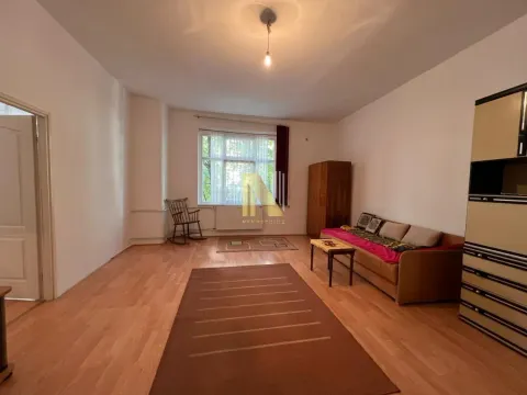 Spacious living room with a sofa, rugs, and a window facing outside. - image 5