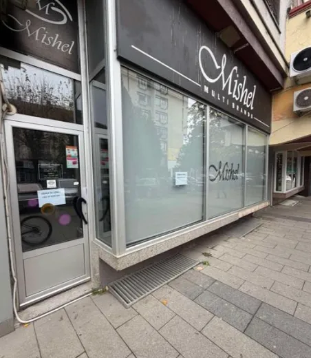 Exterior view of a commercial space with a shop window and business sign.