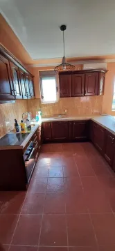 Kitchen with dark wooden cabinetry, ceramic tiles, and a window. - image 9