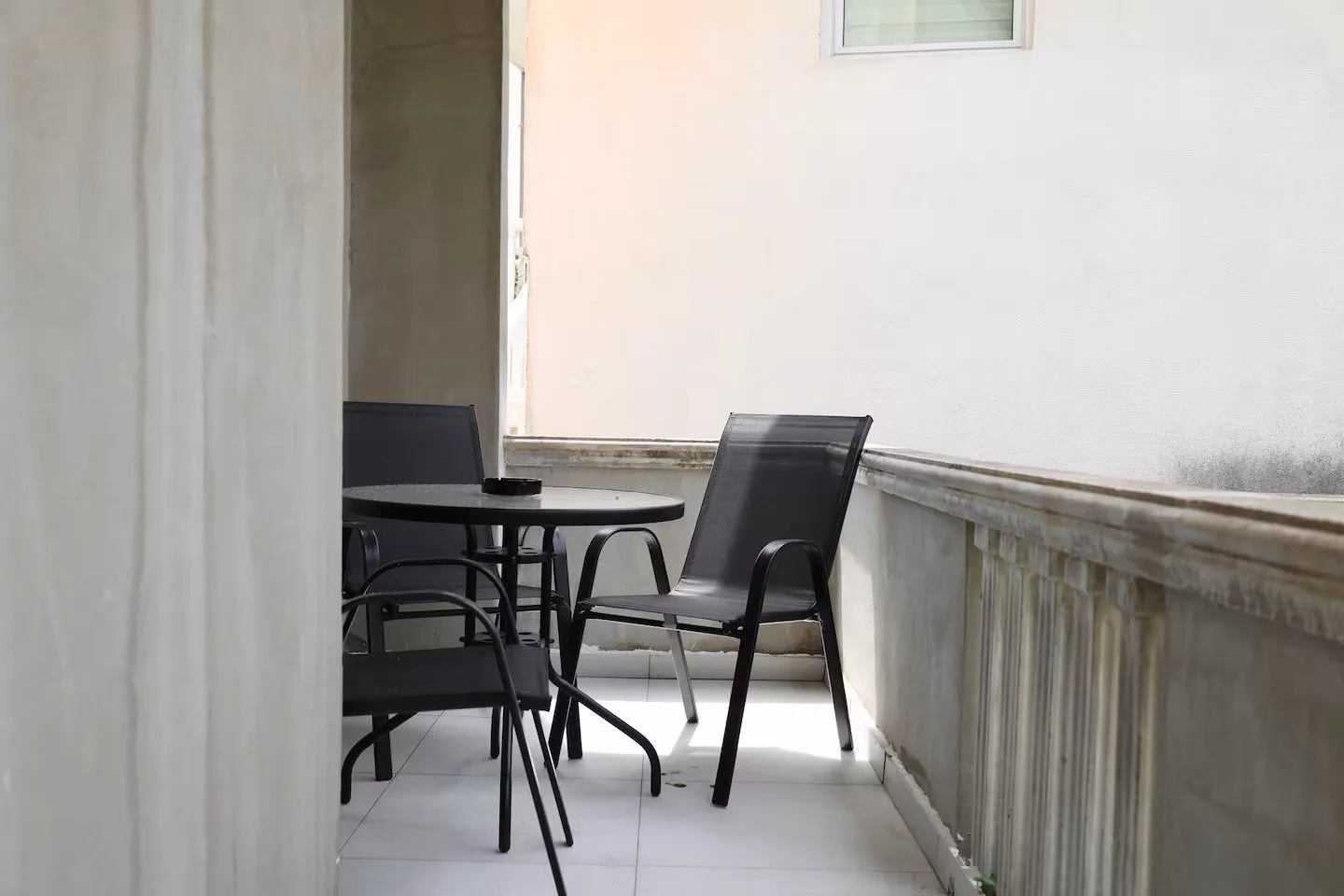 Natkrivena terasa sa crnim baštenskim stolom i stolicama.