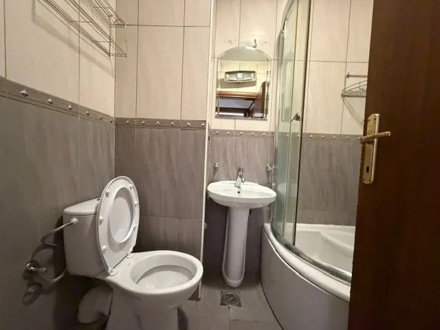 Manje kupatilo sa tuš kabinom, lavaboom i toalet šoljom.