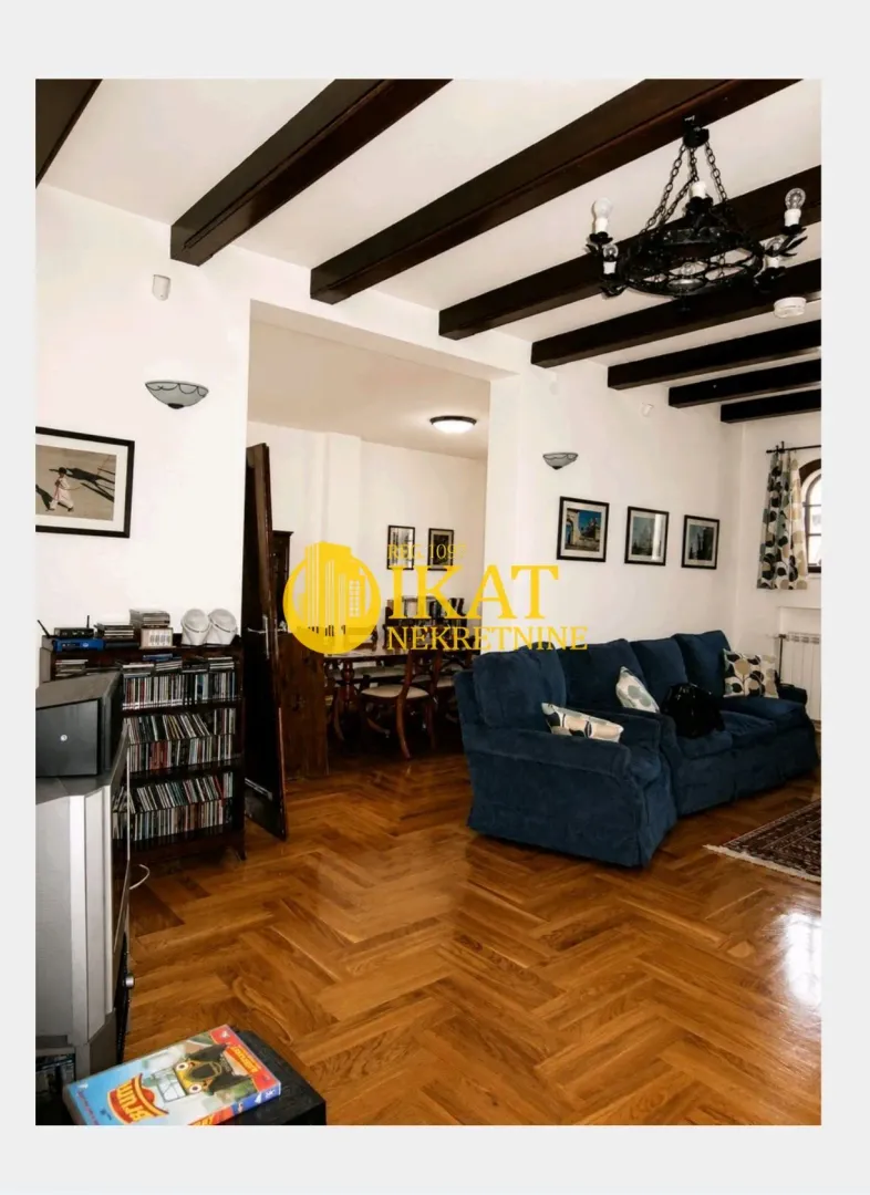 Living room with a blue sofa, wooden flooring, and decorative ceiling beams.
