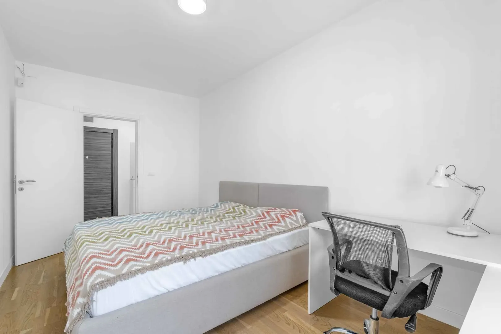 Bright bedroom with a double bed and a desk.
