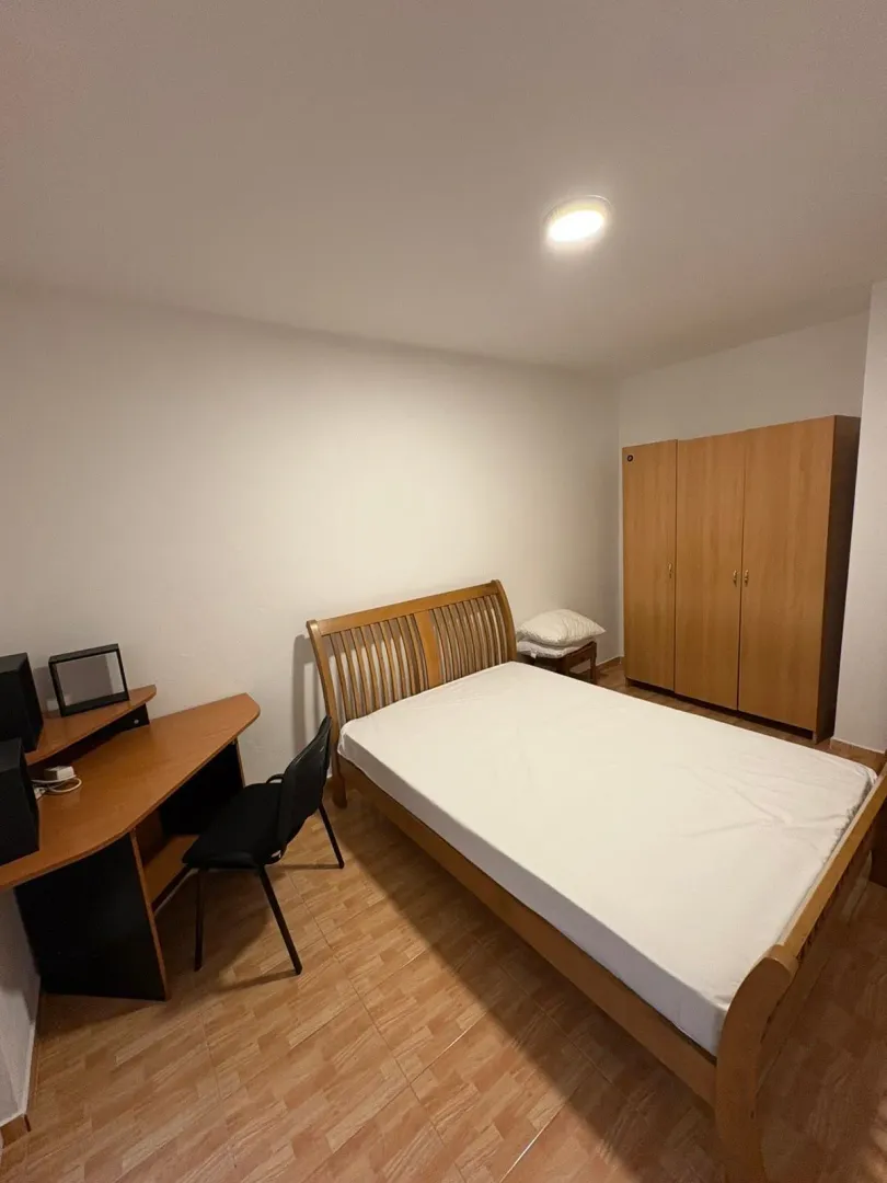 Furnished bedroom with a double bed, desk, and wardrobe.