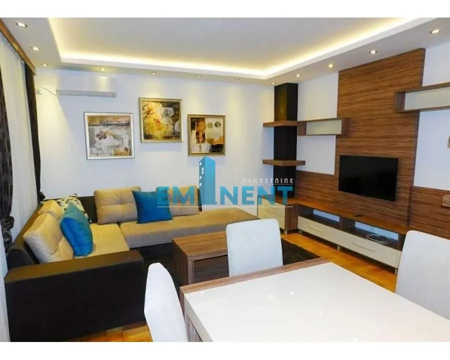 Living room with a sofa set, TV unit, and dining table.