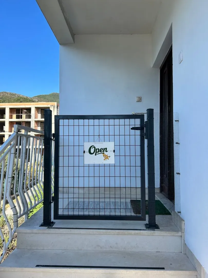 Entrance door and a small metal gate with an open sign on the building stairs.