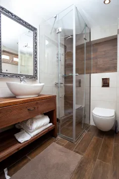 Modernly equipped bathroom with wooden elements, a walk-in shower, and a wall-mounted toilet. - image 12