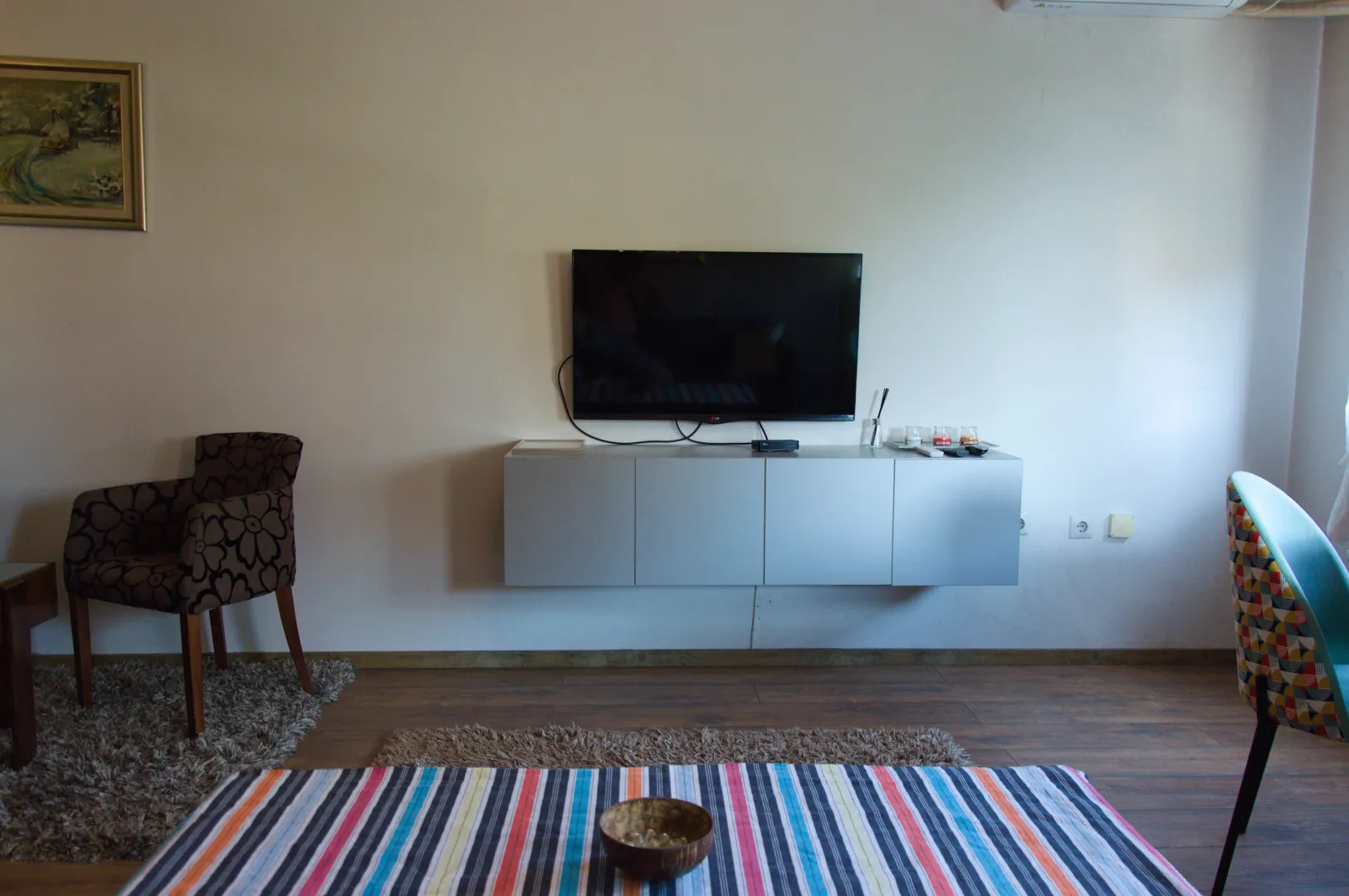 Living room with a TV, sideboard, and armchairs.