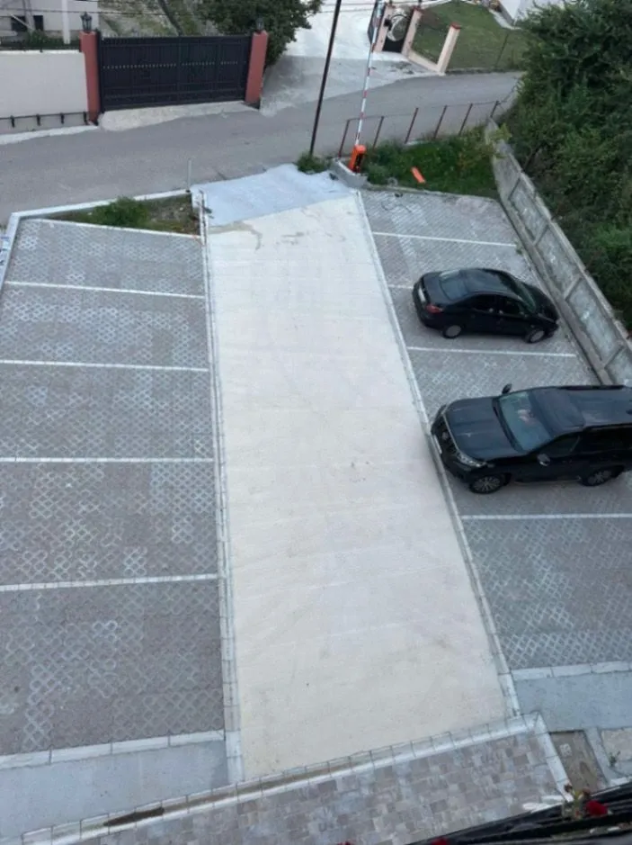 Pogled odozgo na popločani parking prostor sa označenim parking mjestima.
