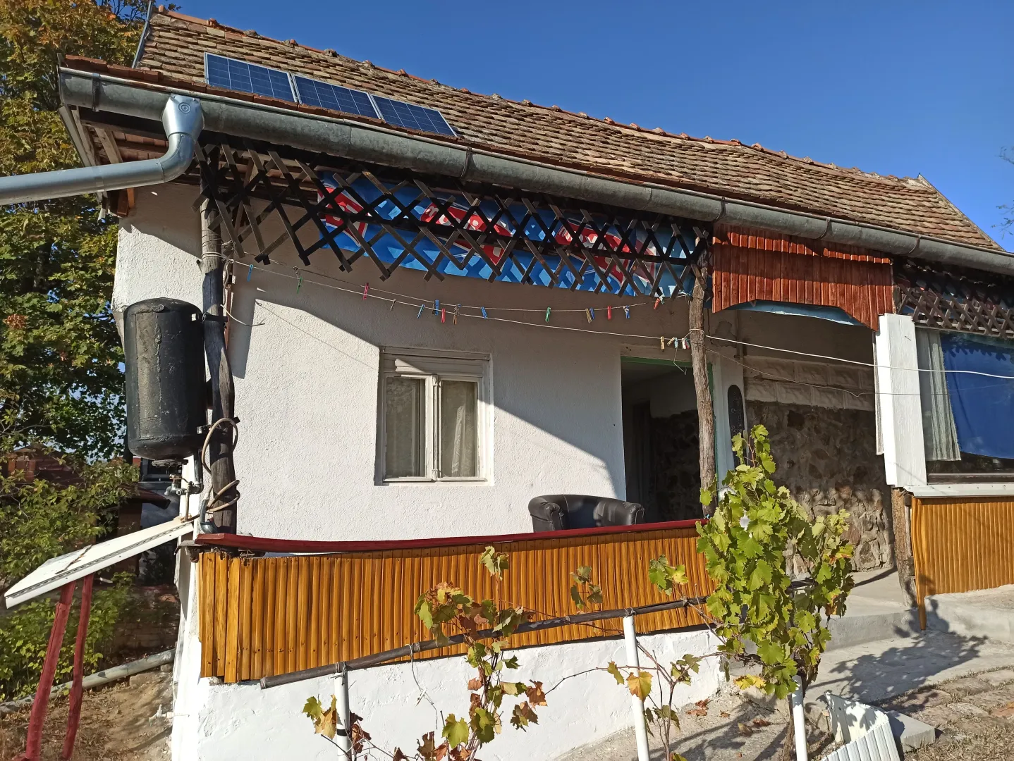 Spoljašnji izgled starije kuće sa terasom i solarnim panelima na krovu.