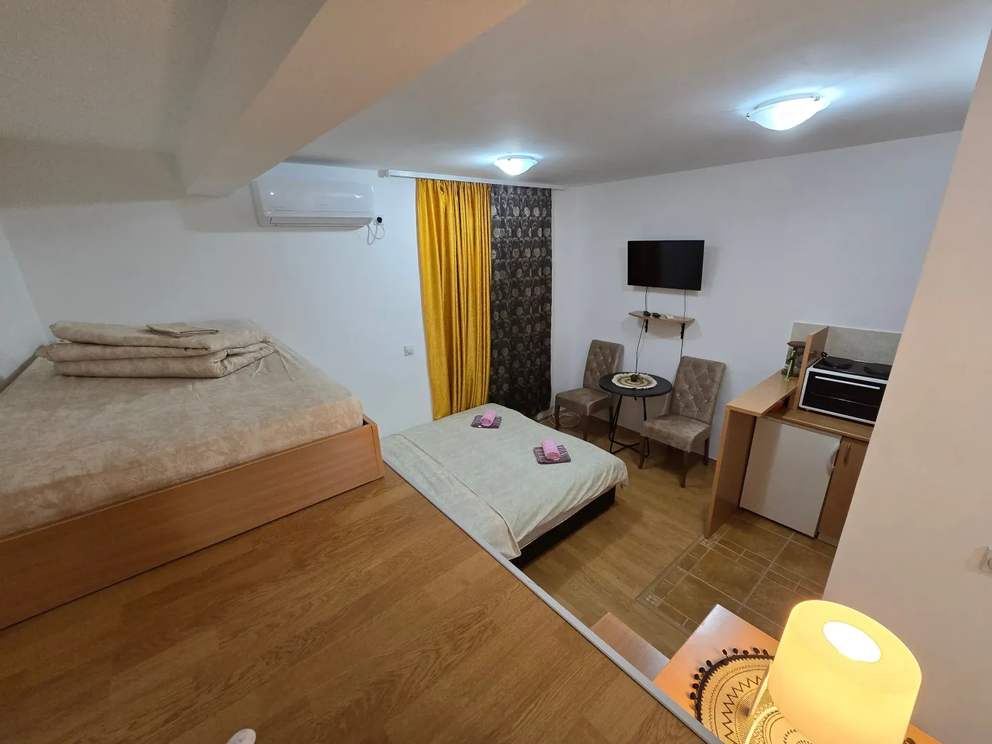 Small furnished room with two beds, air conditioning, and a kitchenette.