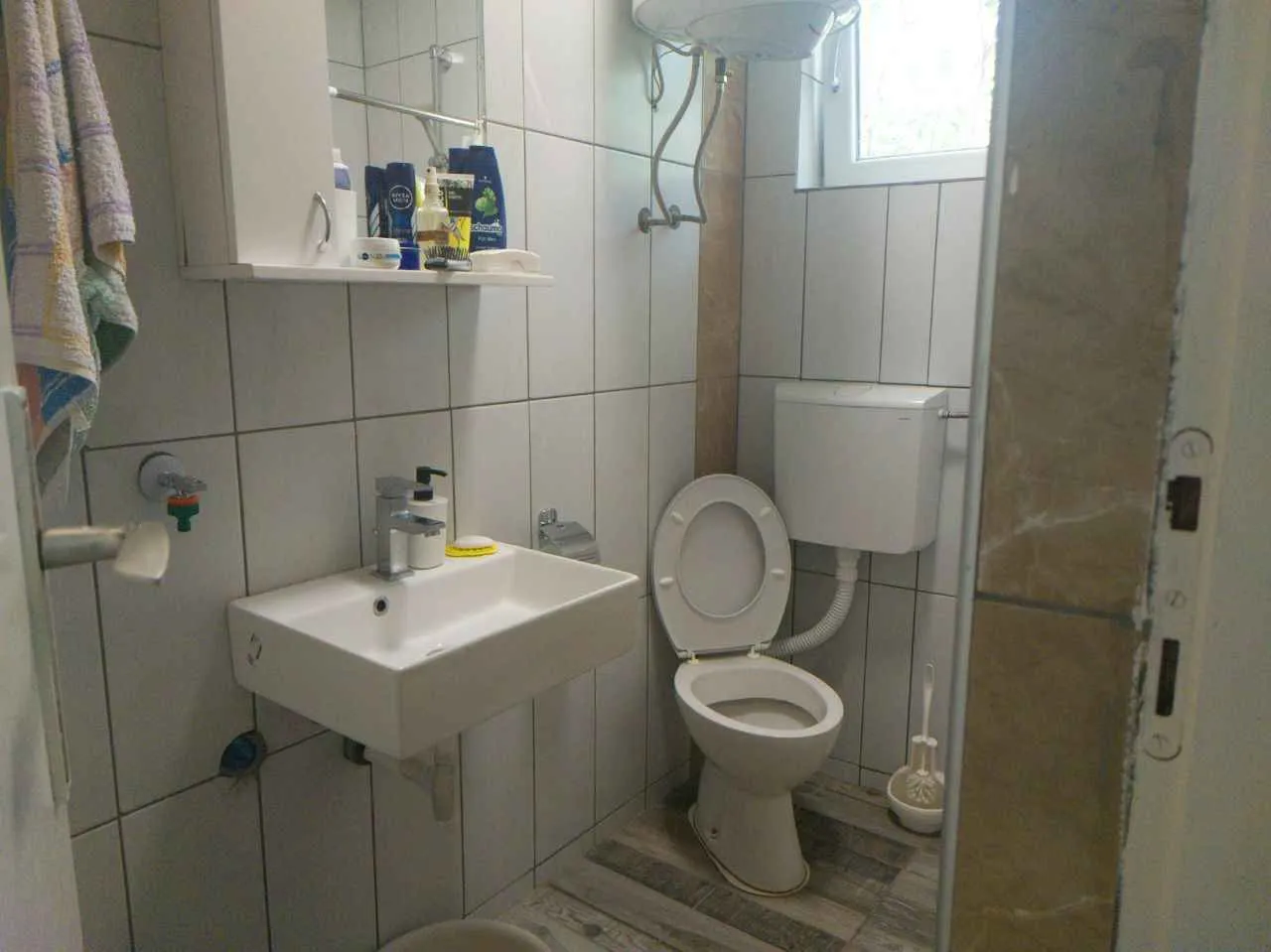 Malo kupatilo sa lavaboom, ogledalom i toaletom.