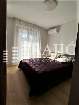 Furnished bedroom with a double bed, white curtains, and an air conditioning unit. - image 11