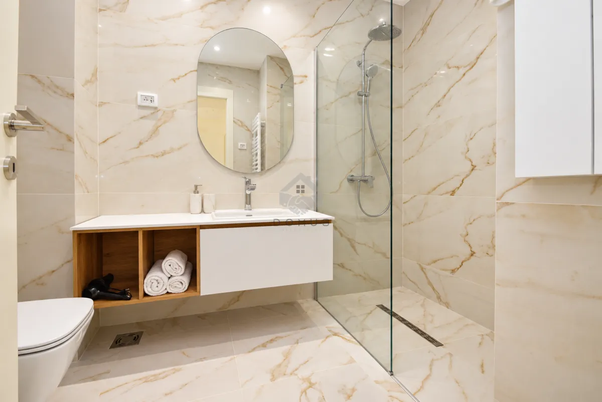 Modernly equipped bathroom with a walk-in shower, washbasin, and mirror.