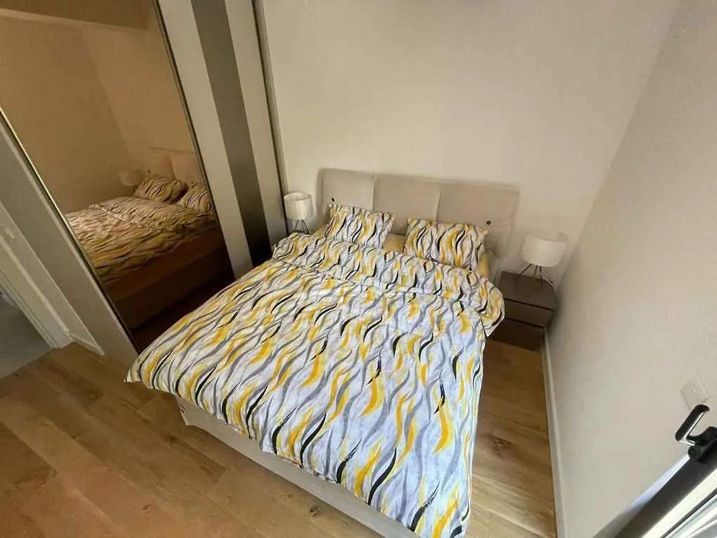 Spavaća soba sa bračnim krevetom i ugradnim ormarom sa ogledalom.