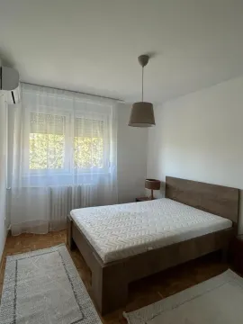 Spavaća soba sa bračnim krevetom, prozorom i klima uređajem. - image 6