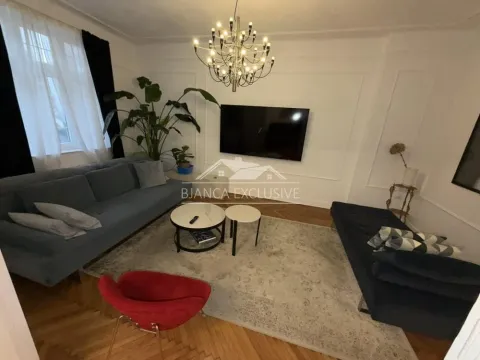 Dnevna soba opremljena garniturom, stočićem, televizorom i ukrasnim biljem. - image 3