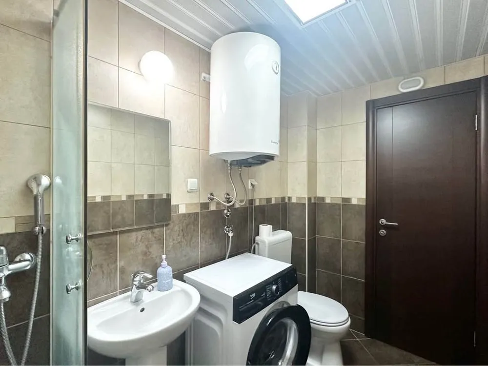 Bathroom equipped with a shower cabin, washbasin, washing machine, and water heater.