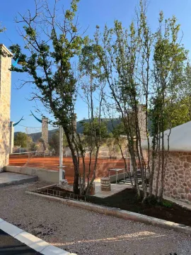 View of the tennis court and the courtyard in front of the stone house. - image 12