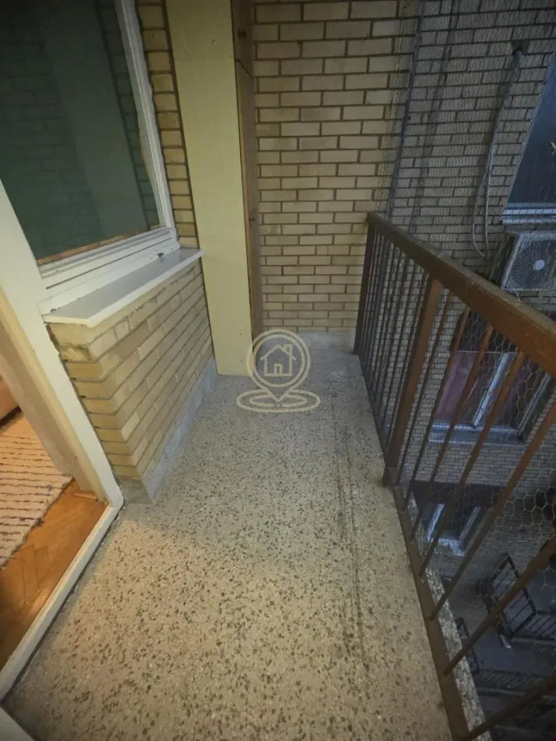 Manji balkon sa metalnom ogradom i pogledom na unutrašnje dvorište.