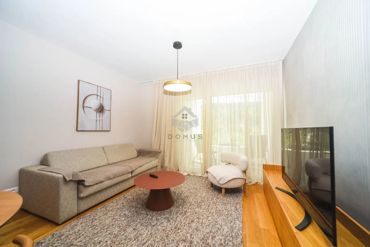 Living room with a sofa, coffee table, TV and access to the terrace.