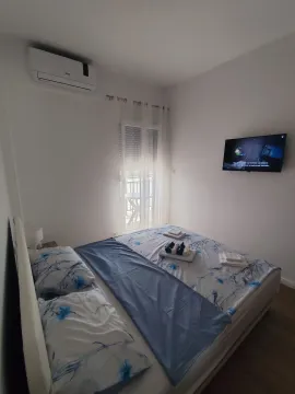 Uređena spavaća soba sa bračnim krevetom, televizorom i klima uređajem. - image 5