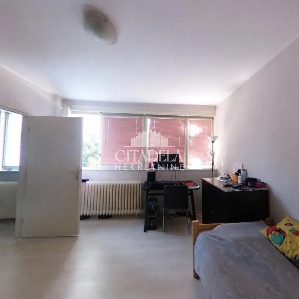 Small bedroom with a bed, a desk, and a window.