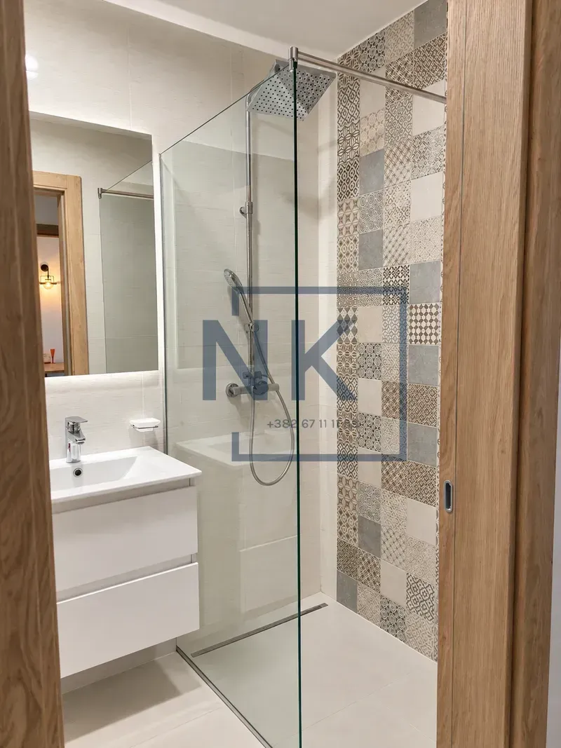 Modern bathroom with a walk-in shower, washbasin, and mirror.
